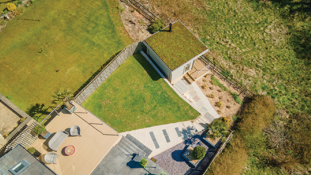 Aerial view of a house with a green roof and surrounding garden.